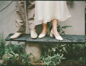 Detail shot of bride and groom's feet standing on a stone bench with ivy and greenery growing beneath