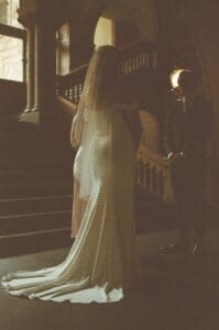Moody film image of a bride and groom standing facing each other during their Pennsylvania wedding ceremony while soft light filters in the backdrop
