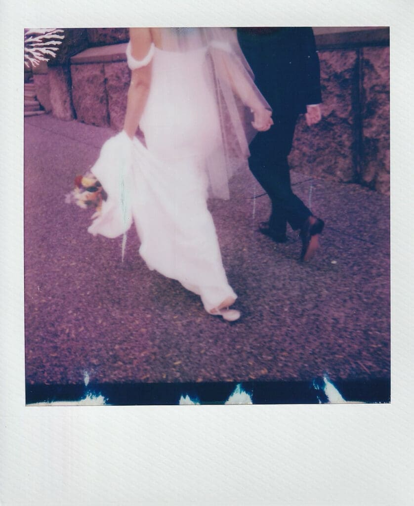 Polaroid detail image of bride and groom walking hand in hand on a stone pathway during their Philadelphia wedding portraits