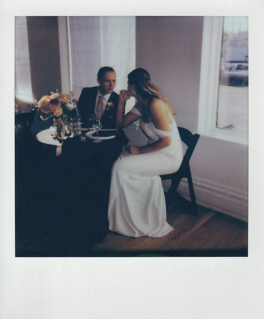 Intimate polaroid image of bride and groom sitting together at a sweetheart table and talking quietly during their Philadelphia wedding reception