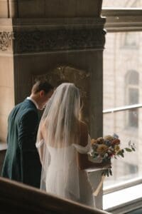Bride and groom sharing a quiet moment walking down a staircase inside Allegheny County Courthouse in Pittsburgh