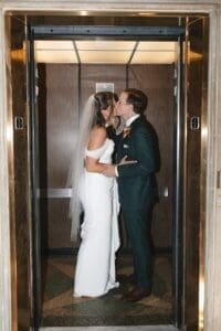 Bride and groom stealing a kiss inside the elevator at Allegheny County Courthouse in Pittsburgh, Pennsylvania — candid just-married moment with ornate marble surroundings, documentary wedding photography