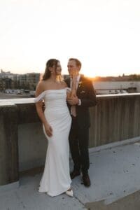 Bride and groom sharing a tender moment at golden hour on a rooftop parking deck in downtown Pittsburgh, Pennsylvania — intimate wedding portrait with warm sunset light behind them, shot on digital