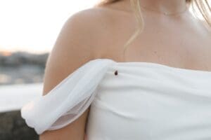 Close-up detail of a bride's off-shoulder wedding gown with a ladybug resting on the fabric, photographed at dusk near the Allegheny County Courthouse in Pittsburgh — candid wedding detail by Shiloh Leath Photography