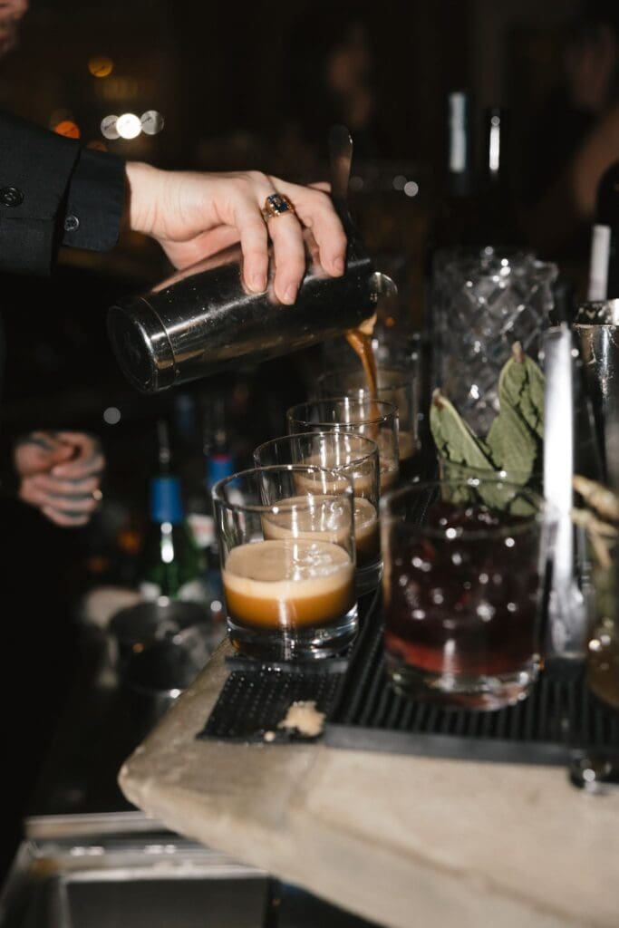 Bartender pouring an espresso martini into glasses at the bar