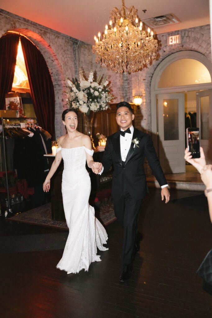 Bride and groom beaming during their grand entrance into the wedding reception