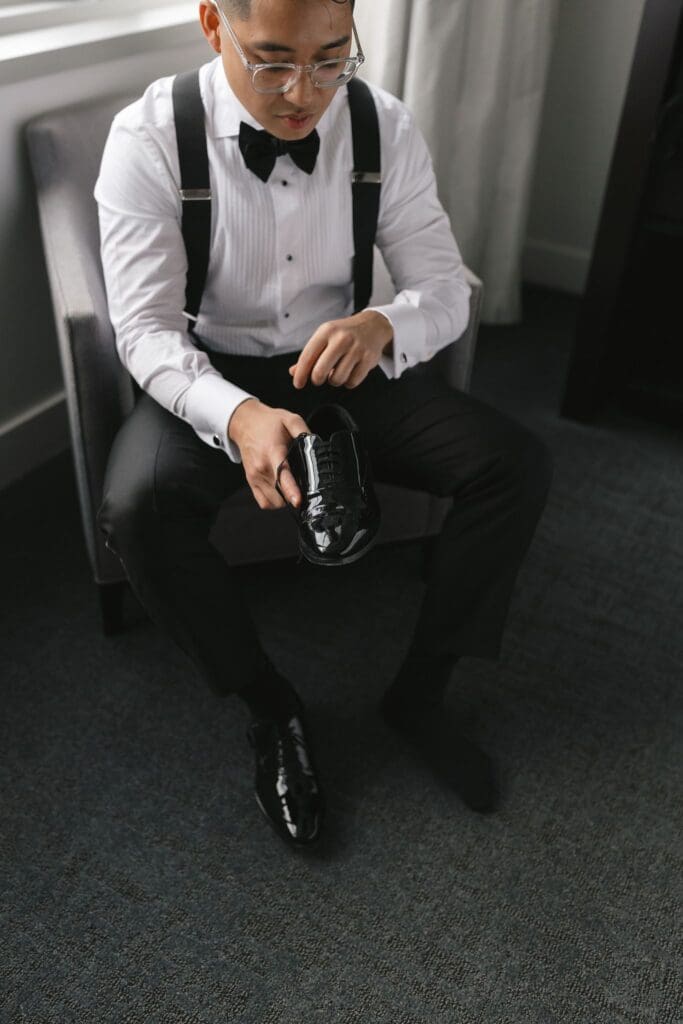 Groom holding his polished black shoe while getting ready