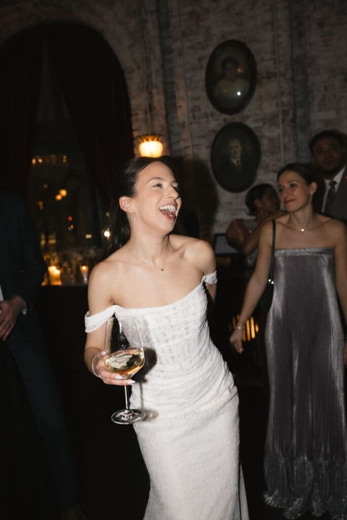 Bride laughing with a glass of wine on the reception dance floor