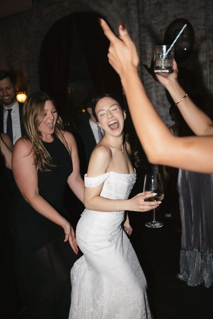 Bride dancing and laughing with friends at the wedding reception