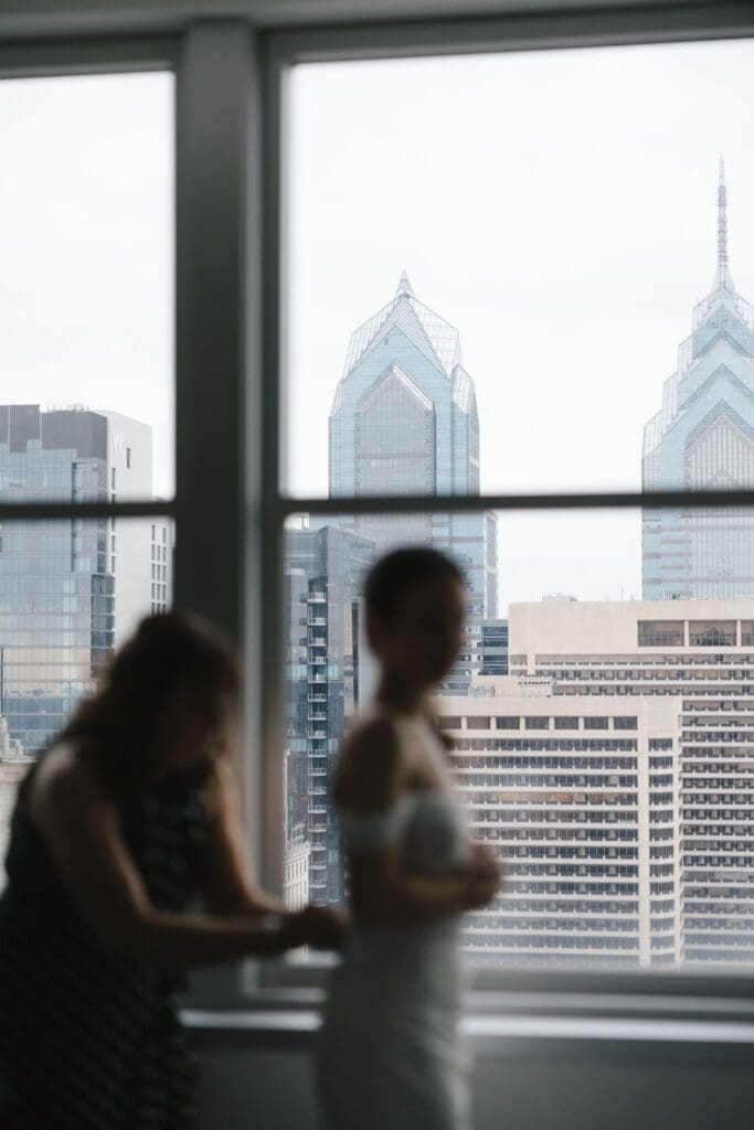 Bride getting ready in a downtown Philadelphia hotel with the Liberty Place towers framed in the window