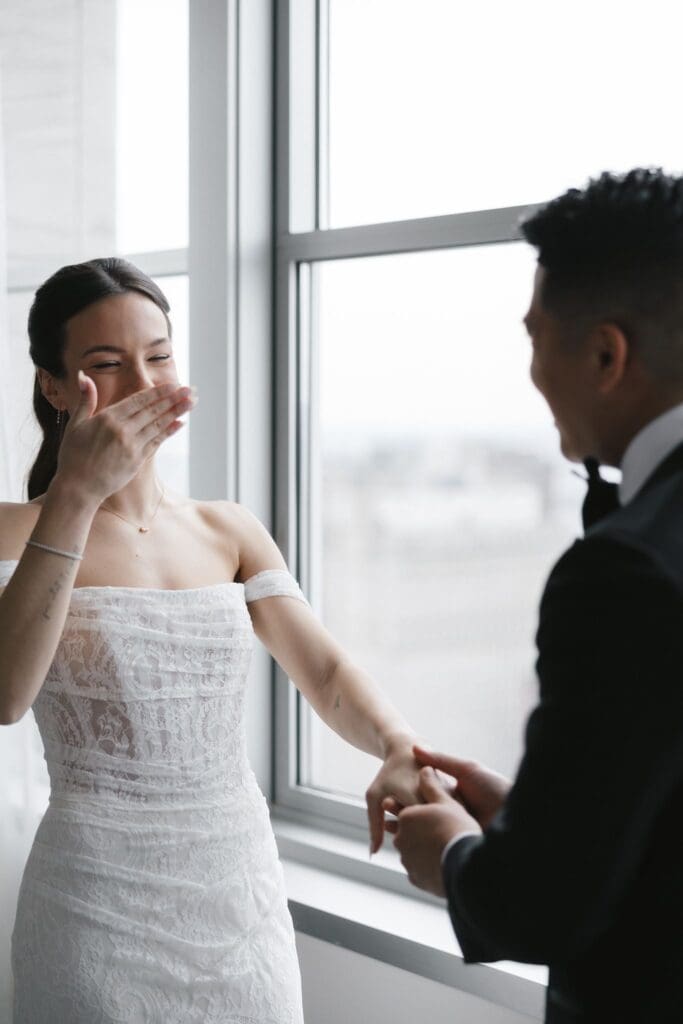 Bride laughing during the couple's first look, holding her groom's hand