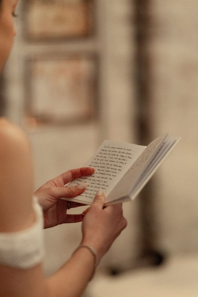 Close-up of the bride's hands holding a handwritten vow book during the ceremony