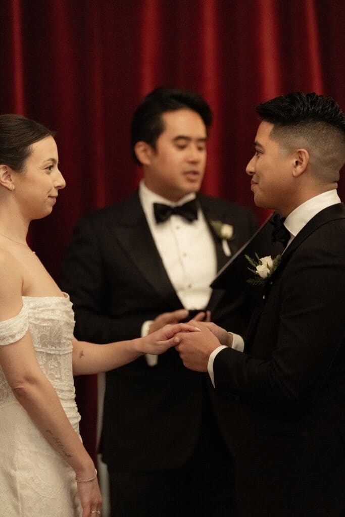 Couple holding hands as their officiant speaks during an intimate candlelit ceremony