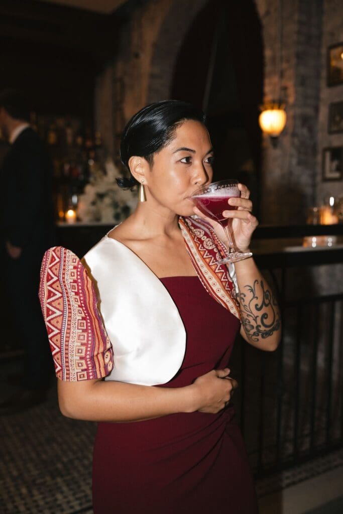 A guest in a traditional Filipino terno enjoying a cocktail during cocktail hour