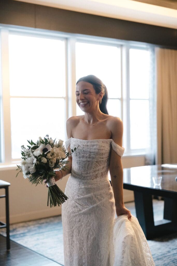 Bride holding her bouquet in an off-the-shoulder lace wedding dress