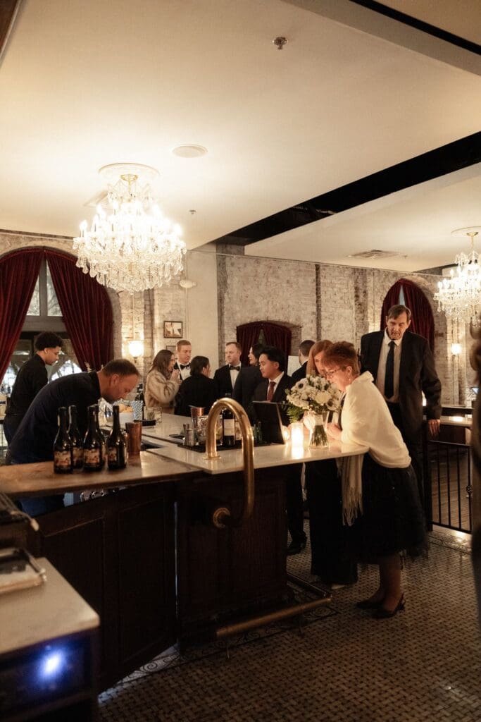 Guests gathered at the marble bar beneath crystal chandeliers at Cicala at The Divine Lorraine