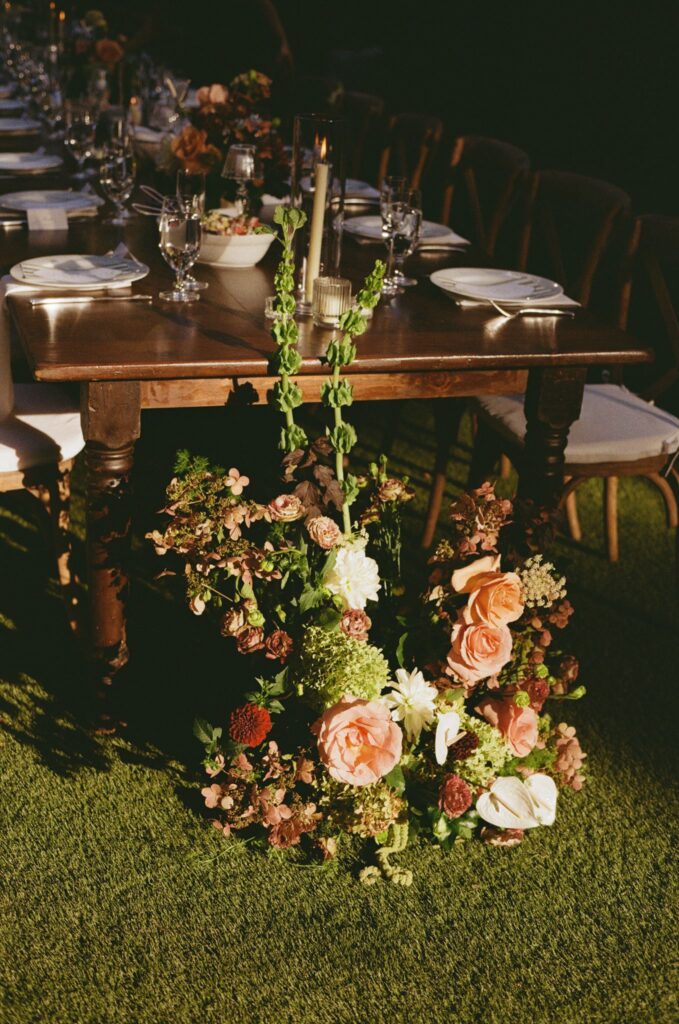 Film photo of a warm pink and burgundy flower arrangement sitting next to a wooden banquet table at Powel House in Philadelphia