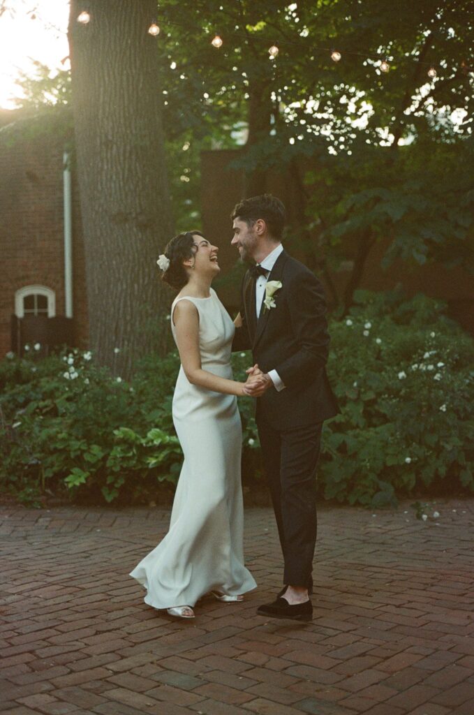 Bride and groom dance under market lights on a brick patio at Powel House in Philadelphia