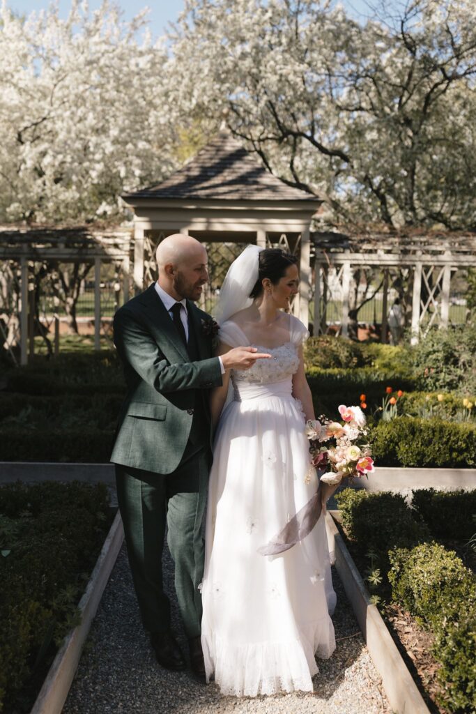 Bride and groom stand on a stone pathway in front of a pergola in the 18th Century Garden in Philadelphia's Old City
