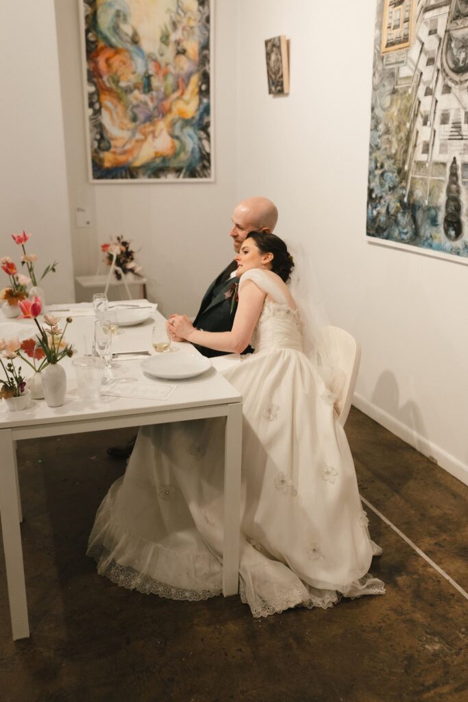 Bride leans on groom while they sit in chairs at Frieda during their micro wedding in Philadelphia