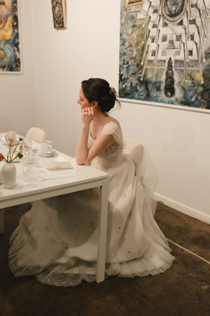 Bride sits at a low white table during cocktail hour at Frieda for a micro wedding in Philadelphia