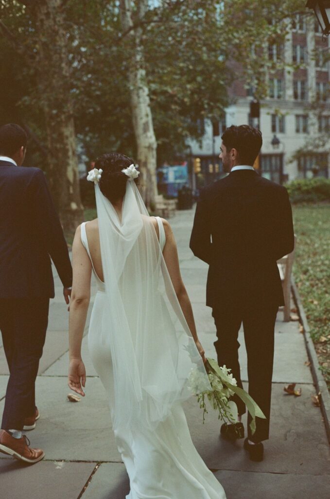 Bride and groom walk down a city sidewalk in Philadelphia