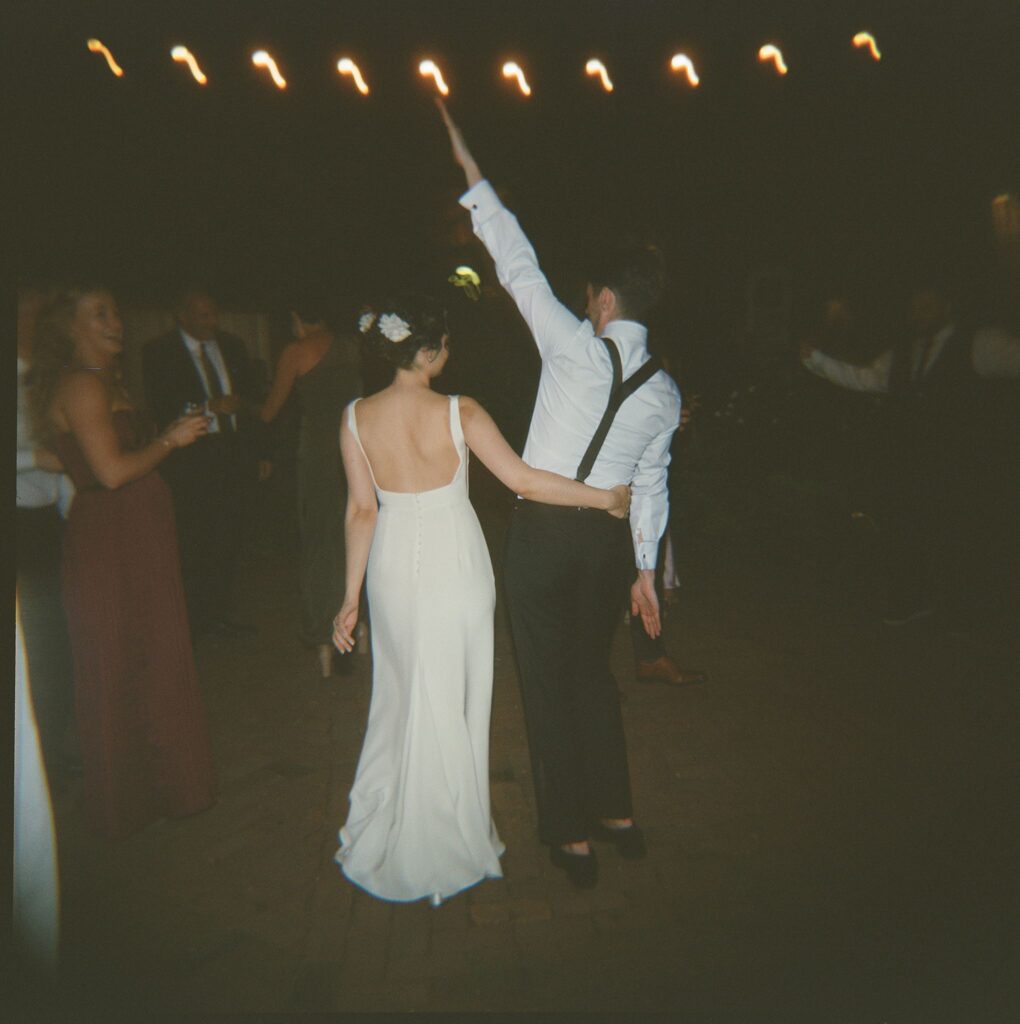 Blurry film capture of bride and groom dancing under string lights at night