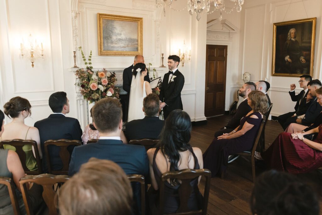 Bride and groom say their vows in front of an intimate gathering of wedding guests inside the Powel House venue in Phildelphia